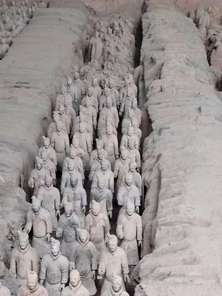 Terracotta warriors standing in rows in an excavation pit