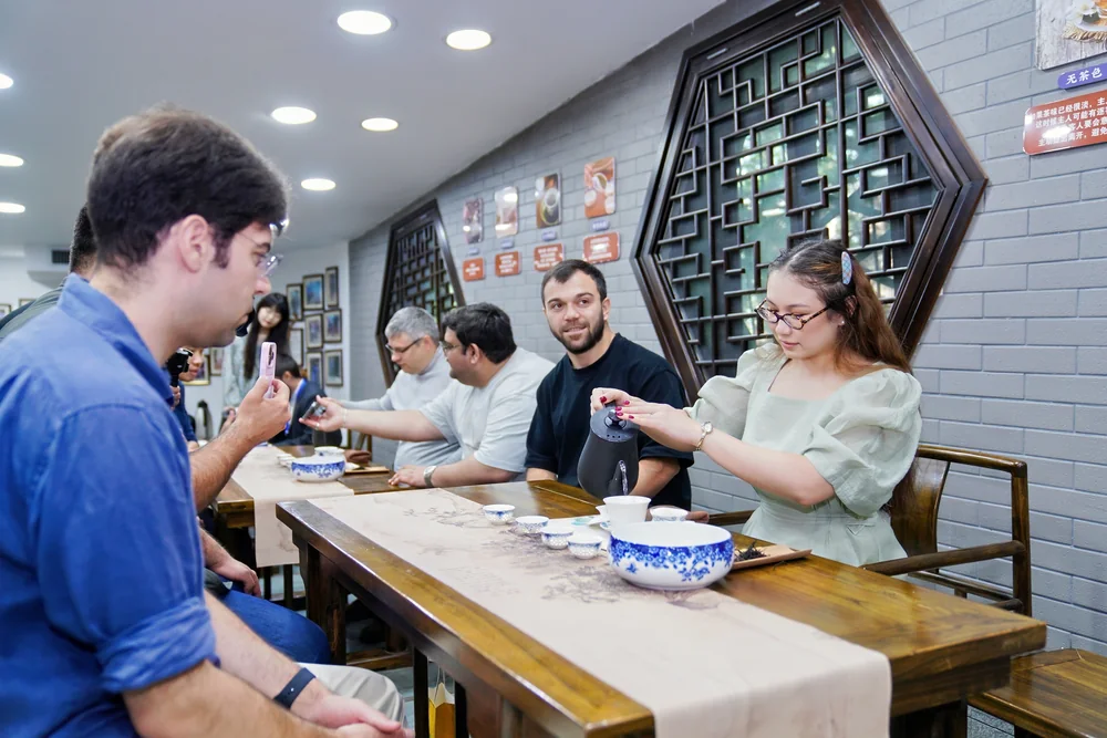 A tea art teacher pouring tea for seated international students