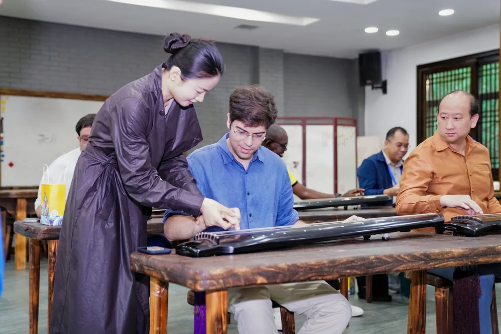 A teacher guiding an international student at a guqin