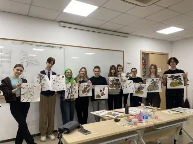 International students holding up their Chinese paintings after a class