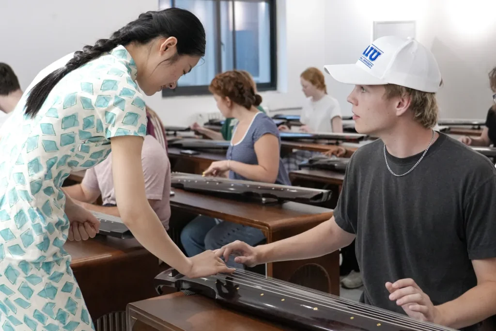 A teacher giving one-to-one guidance at a guqin